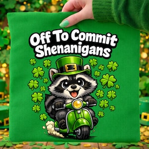 Może przedstawiać: Zielona poszewka na poduszkę z napisem "Off To Commit Shenanigans". Przedstawia kreskówkowego szopa w zielonym kapeluszu jadącego na zielonym skuterze, otoczonego zielonymi koniczynami, na Dzień Świętego Patryka.