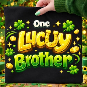 Puede incluir: Bolso tote negro con las palabras "One Lucky Brother" en amarillo y verde, decorado con tréboles, monedas de oro y estrellas. El bolso lo sostiene una persona con esmalte de uñas verde.
