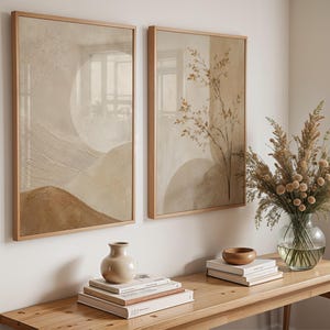Peut inclure: Deux cadres muraux rectangulaires présentant des paysages abstraits texturés dans des tons beige, crème et brun. L'impression de gauche montre des collines superposées, tandis que celle de droite affiche de délicates branches botaniques.