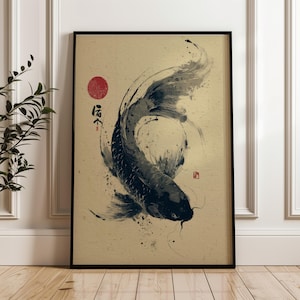 May include: Framed art print featuring a stylized black koi fish swimming upwards. The artwork has a traditional Japanese aesthetic, with a red sun and calligraphy on a beige background. The fish is rendered with brushstrokes.