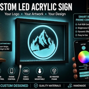 May include: A rectangular custom LED acrylic sign with a black 3D printed frame featuring a glowing light blue mountain and forest graphic inside a circle. The sign includes smart RGB phone control, USB-C power, and wall mountable capabilities.