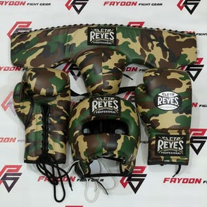 Könnte beinhalten: Ein komplettes Box-Set im Camouflage-Muster, einschließlich Handschuhen, Kopfschutz und Brustschutz. Die Handschuhe und der Kopfschutz tragen das Logo "CLETO REYES PROFESIONAL". Das Set ist für den Schutz beim Training und Wettkampf konzipiert.
