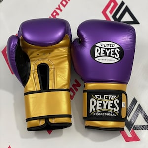 Luvas de boxe Cleto Reyes em couro legítimo, nas cores dourado e roxo, ideais para academia.