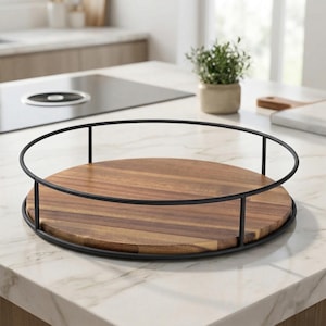 Puede incluir: Una bandeja redonda de madera para servir con un marco de metal oscuro. La bandeja tiene un patrón de vetas de madera natural y está colocada sobre una encimera blanca. El marco de metal tiene una parte superior circular y soportes verticales.