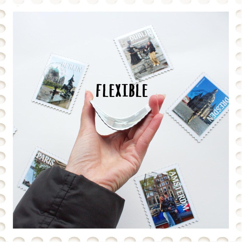 May include: A flexible, white-backed magnet is bent to show its pliability. The word "FLEXIBLE" is printed in black. Surrounding the magnet are postage stamp-style magnets with images of Berlin, Dublin, Dresden, Paris, and Amsterdam.