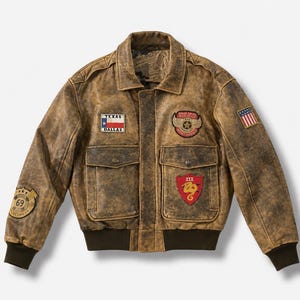 May include: A distressed brown leather bomber jacket featuring a Texas Dallas flag patch, a winged crest patch, a red shield patch with a yellow snake, a circular 69 patch on the sleeve, and a small American flag patch on the upper left shoulder.