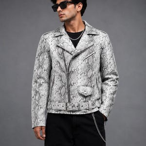 May include: A white and gray snakeskin-patterned jacket with a black zipper, belt, and pocket details. The jacket has a classic biker style with a notched collar and a fitted silhouette. The jacket is worn with black pants.