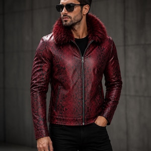 May include: A red and black snakeskin-patterned jacket featuring a prominent dark red faux fur collar, a full-length front zip, and long sleeves. The jacket is worn over a plain black shirt and paired with black trousers, complemented by dark sunglasses.