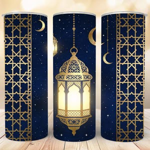 May include: A tumbler with a navy blue background featuring a gold lantern, crescent moons, and stars. The tumbler has a gold geometric pattern on the sides. The design evokes a celestial and cultural theme.