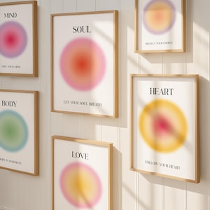 May include: Several framed art prints with a minimalist design. Each print displays a blurred, colourful circular design with words such as "Mind," "Soul," and "Heart." The prints are in wooden frames and mounted on a white wall.