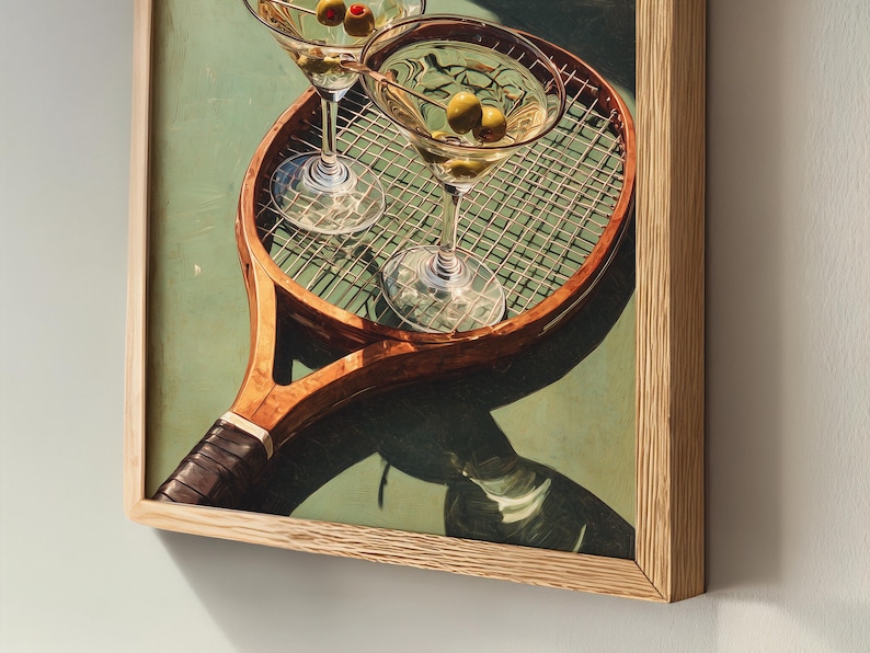 May include: Framed print of two martini glasses with olives on a vintage tennis racket. The artwork has a light green background and a wooden frame, creating a classic and stylish aesthetic.