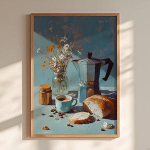 Puede incluir: Pintura enmarcada de naturaleza muerta que representa una escena de café. Incluye una cafetera italiana plateada, una taza azul con café, un pan, un tarro de granos de café y un jarrón de flores silvestres. La paleta de colores es suave con tonos azules, marrones y blancos.