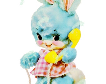 Könnte beinhalten: Ein blaues Plüsch-Hasenspielzeug, das ein gelbes Spielzeugtelefon und ein weißes Seil hält. Der Hase trägt ein rosa-weißes Gingham-Kleid.