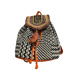 May include: A black and white patterned backpack with an orange trim and drawstring closure. The flap features colorful embroidery and embellishments. An orange tassel hangs from the drawstring. The backpack is designed with a geometric pattern.