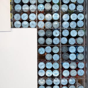 May include: A clear acrylic organizer drawer filled with numerous spools of Kreinik metallic thread. Each spool features a white circular label with black text indicating the specific color number and thread type, arranged in neat rows.
