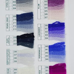 May include: Color chart featuring swatches of yarn in various shades, including taupe, steel gray, pearl gray, black/charcoal, warm gray, white/cream, violet, grape, plum, lavender, periwinkle, and fuchsia. Each color is labeled with a number.