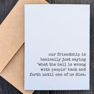 May include: A white greeting card with black text that reads "our friendship is basically just saying 'what the hell is wrong with people' back and forth until one of us dies." The card is paired with a brown envelope.
