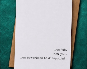 May include: A white greeting card with black typewriter-style text that reads: new job. new you. new coworkers to disappoint. The card is placed on top of a brown kraft paper envelope, featuring a clean and minimalist design aesthetic.