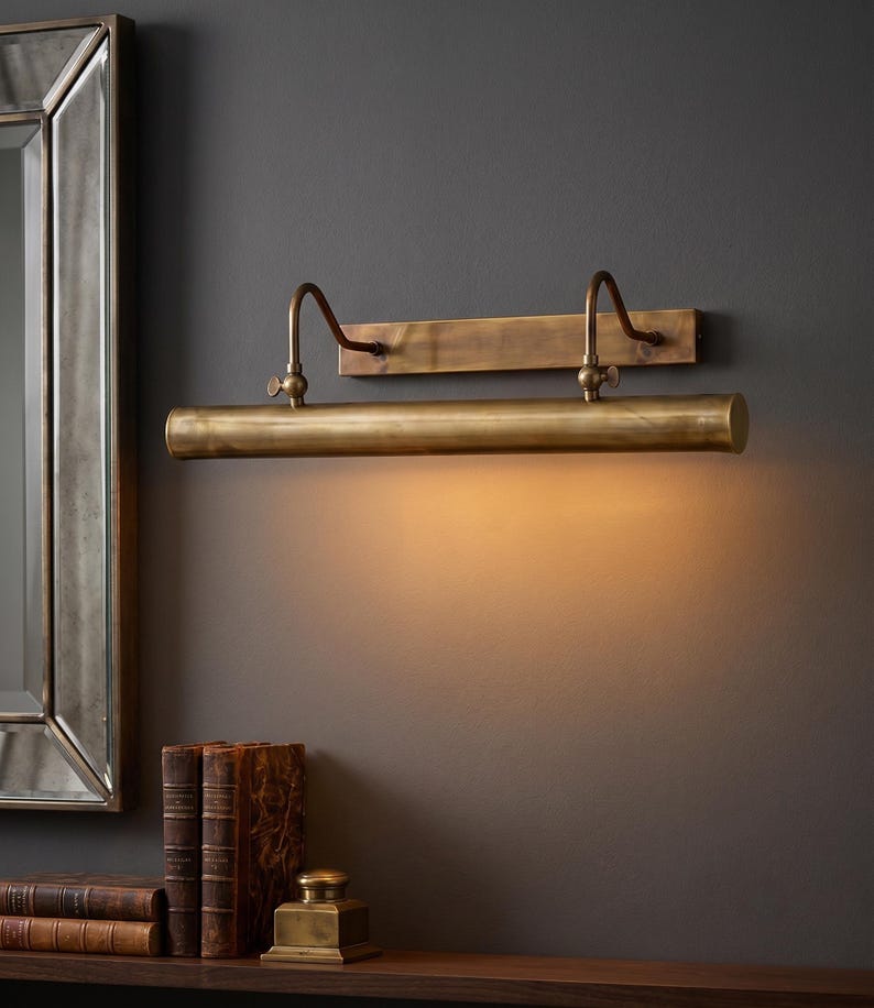 Vintage brass gallery wall light installed above artwork in luxury home office library.
