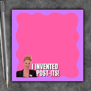 May include: A square sticky note with a light purple border and a bright pink center. The note features an image of a person with blonde hair wearing a black blazer, accompanied by the white text that reads, I INVENTED POST-ITS!