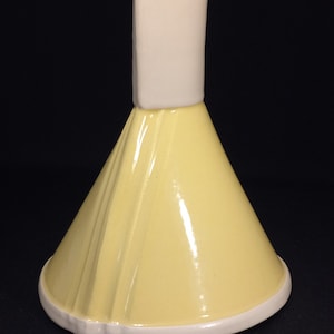 May include: A yellow ceramic lid with a white rim and a white rectangular top. The lid is shaped like a cone and has a glossy finish.