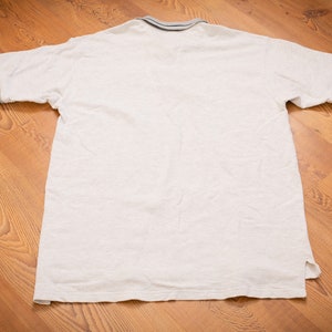 May include: A white short-sleeved polo shirt with a blue and white striped collar and cuffs.