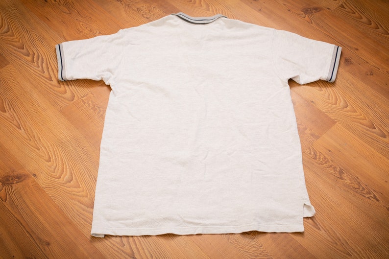 May include: A white short-sleeved polo shirt with a blue and white striped collar and cuffs.
