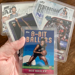 May include: A collection of basketball trading cards featuring Ace Bailey of the Utah Jazz. The cards are in protective sleeves. One card has "8-BIT BALLERS" text and a pixelated image of Bailey. Other cards show Bailey in action.