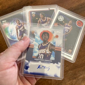May include: A collection of basketball trading cards featuring Rasheer Fleming of the Phoenix Suns. The cards are in protective sleeves and include the Suns logo, player's number 20, and the Topps logo. One card is autographed.