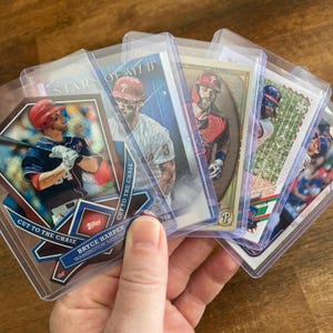 May include: Five baseball trading cards featuring different players. The cards are in protective plastic sleeves. The cards feature the text "Stars of MLB", "Cut to the Chase", "Bryce Harper", "Washington Nationals", and "Topps".