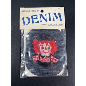 May include: A denim repair patch featuring a cartoon character with red hair, a black hat, and a checkered shirt. The patch is iron-on and comes in a clear plastic package. The text "DENIM REPAIR PATCH" is printed on the packaging.