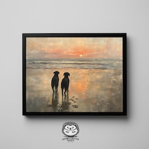 Puede incluir: Una impresión enmarcada que representa a dos perros negros en una playa al atardecer. La obra de arte utiliza una paleta de colores cálidos de naranja, rosa y gris. Huellas de patas son visibles en la arena mojada. La impresión está en un marco negro.