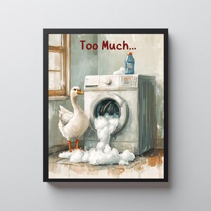 Op de afbeelding: Een ingelijste kunstdruk toont een wasmachine die overloopt met schuim, een fles wasmiddel en een witte gans. De tekst "Too Much..." staat boven de wasmachine. Het kunstwerk is in aquarel stijl.