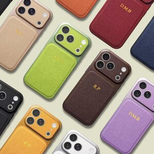 Peut inclure: Une collection d'étuis pour smartphone dans diverses couleurs, notamment vert lime, brun foncé, rouge, jaune, violet, noir et blanc. Chaque étui présente une finition texturée, une découpe pour triple objectif et des initiales dorées comme D.M.B ou R.P.