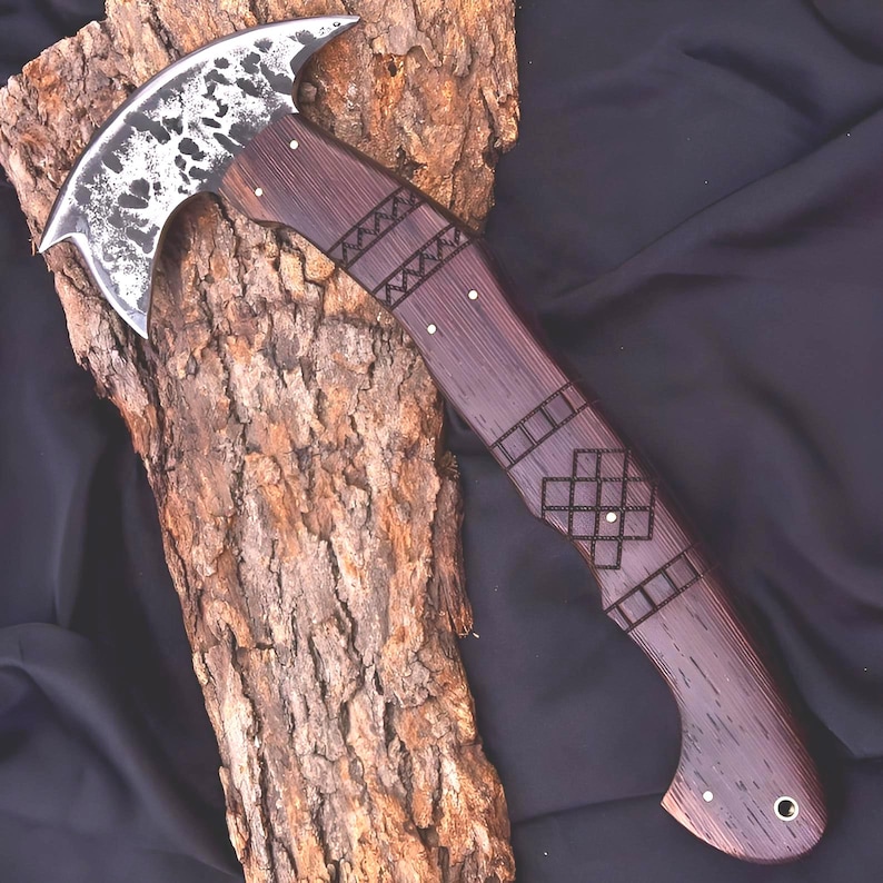 Peut inclure: Une hache artisanale avec une lame en acier incurv&eacute;e et textur&eacute;e et un manche en bois fonc&eacute;. Le manche pr&eacute;sente des motifs d&eacute;coratifs grav&eacute;s et est mont&eacute; sur un morceau de bois textur&eacute;. La hache est con&ccedil;ue pour l'utilit&eacute; et l'exposition.