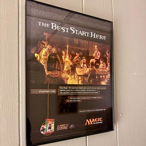 May include: Framed poster for Magic: The Gathering Academy, with the text "THE BEST START HERE." The image depicts a group of people playing a card game. The poster also includes the website playmagic.com and the Magic: The Gathering logo.