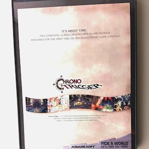 May include: A framed game case for Chrono Trigger, featuring the game's logo and artwork. The text reads "IT'S ABOUT TIME - TWO COMPLETE, CLASSIC ADVENTURES IN ONE PACKAGE." The SquareSoft logo is visible at the bottom.