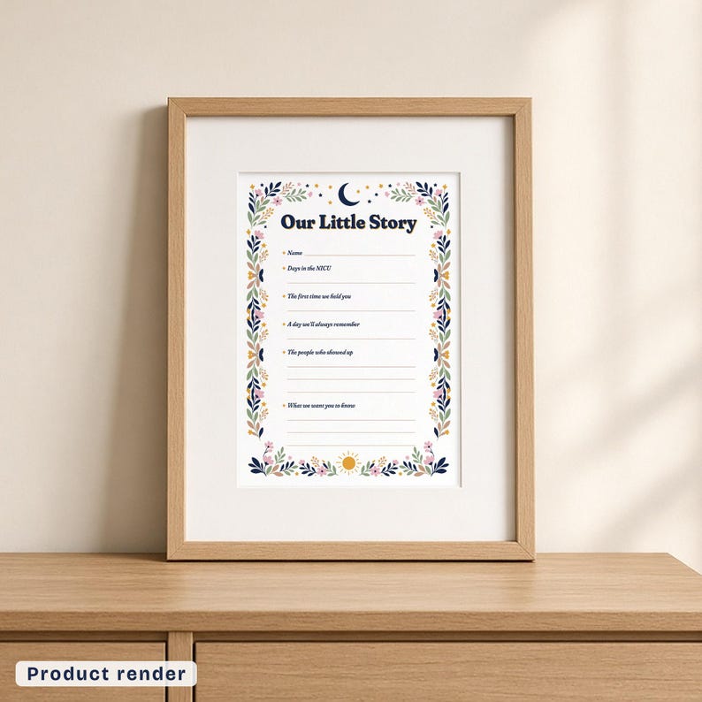The Our Little Story page in a light wood frame with a wide white mat, standing on a light wood dresser against a cream wall. The page has a navy title, a crescent moon and stars at the top, a sun at the bottom, a border of leaves and flowers, and six labeled spaces with blank lines.