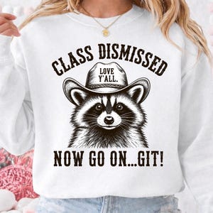 Może przedstawiać: Biała bluza z szopem w kapeluszu kowbojskim. Na kapeluszu napis "LOVE Y'ALL". Nad szopem napis "CLASS DISMISSED", a pod nim "NOW GO ON...GIT!". Projekt jest czarny.