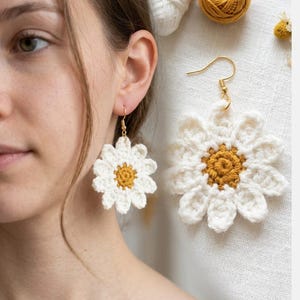 Può includere: Orecchini a margherita all'uncinetto bianchi con ganci color oro. Gli orecchini presentano un design a petali bianchi che circondano un centro giallo. Un accessorio floreale.