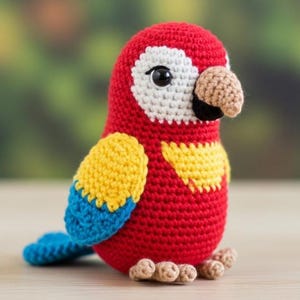 May include: A handmade crochet parrot in vibrant red, yellow, and blue. The bird has a tan beak and feet, with white accents around the eyes. This soft sculpture is a charming decorative item.