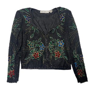Könnte beinhalten: Schwarze, mit Perlen besetzte Jacke mit floralen Stickereien in Rot, Blau und Grün. Die Jacke hat lange Ärmel und einen V-Ausschnitt. Der Markenname "SCALA" ist auf dem Etikett zu sehen.