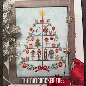 May include: A counted cross stitch pattern titled The Nutcracker Tree by tiny modernist. The design features a stylized Christmas tree decorated with ornaments, a rocking horse, a nutcracker, a ballerina, a clock, and gifts on a light blue background.