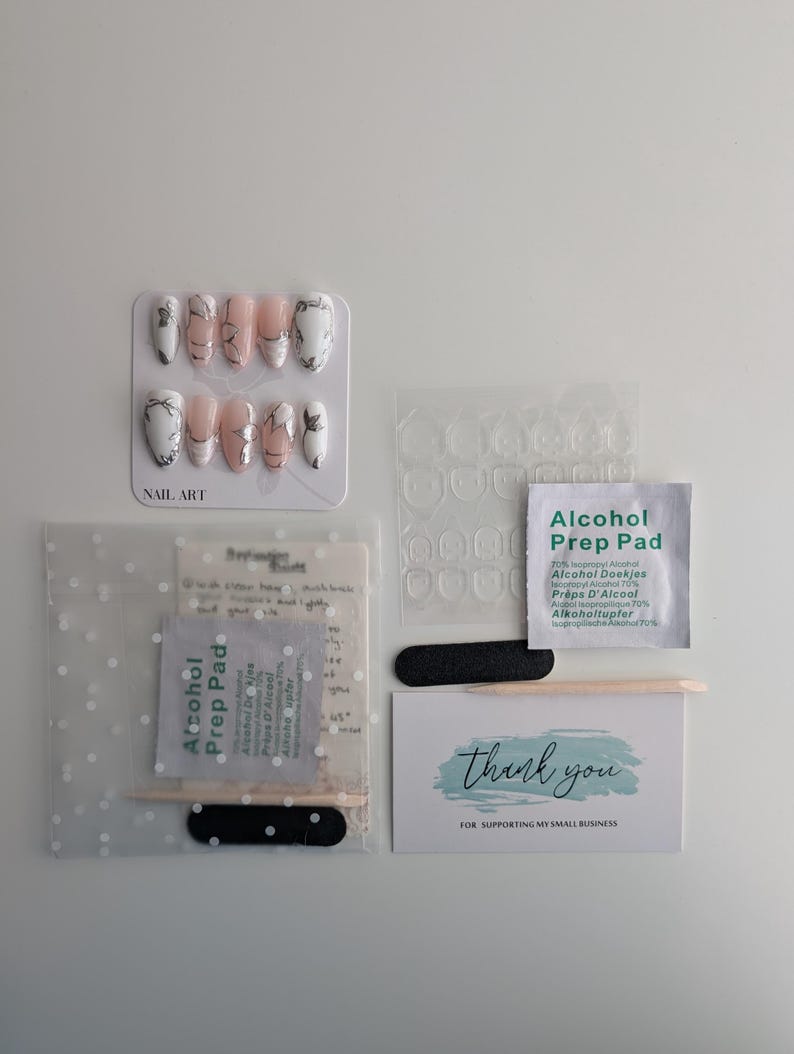 Puede incluir: Un kit de arte de u&ntilde;as con u&ntilde;as postizas, pesta&ntilde;as adhesivas para u&ntilde;as, almohadillas con alcohol, limas de u&ntilde;as y una tarjeta de agradecimiento. Las u&ntilde;as postizas presentan un dise&ntilde;o de m&aacute;rmol con detalles en blanco y negro.