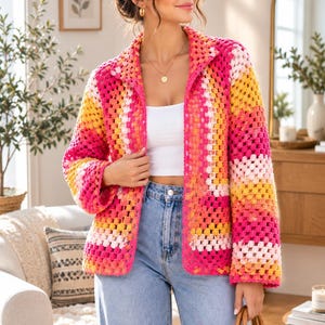 May include: A long-sleeve crochet cardigan featuring a vibrant granny square pattern in shades of hot pink, bright yellow, orange, and white. The open-front jacket has a collared neckline and a boxy fit, paired with light blue denim jeans.