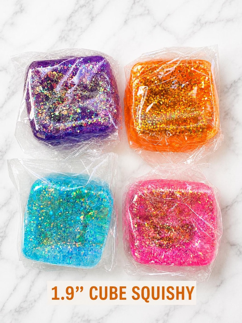 May include: Four 1.9-inch cube squishies wrapped in clear plastic. The set includes one purple, one orange, one blue, and one pink cube, each filled with multi-colored glitter particles that reflect light. The text 1.9" CUBE SQUISHY is visible.