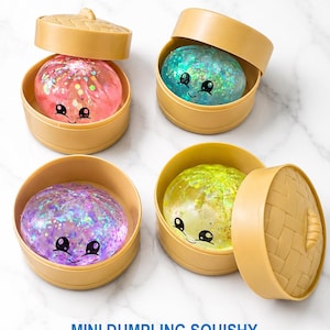 May include: Four round, tan plastic containers resembling bamboo steamers, each holding a translucent, glitter-filled squishy toy shaped like a dumpling. Each toy features a printed smiling face with black eyes and a mouth. Text reads: MINI DUMPLING SQUISHY.
