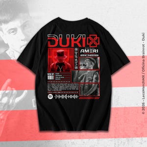 May include: Black t-shirt featuring a red and white graphic design with the text "DUKI AMERI 2025". The design includes images of a person wearing a hat and singing, along with a Spotify code and the text "NEW EP AMERI LEITMOTIV VIDA DE ROCK".