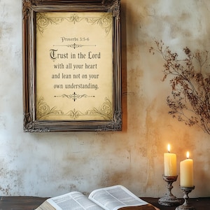 Peut inclure: Une impression encadrée avec le texte "Trust in the Lord with all your heart and lean not on your own understanding." Le cadre est marron foncé avec des détails ornés. Deux bougies allumées et un livre ouvert sont au premier plan.