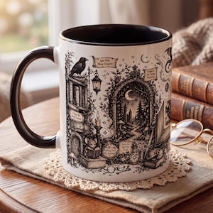 May include: A white ceramic mug with a black handle and interior, featuring a detailed black ink illustration of a fantasy library scene. The design includes a raven, a mouse reading a book, a crescent moon, and text reading Just One More Chapter.